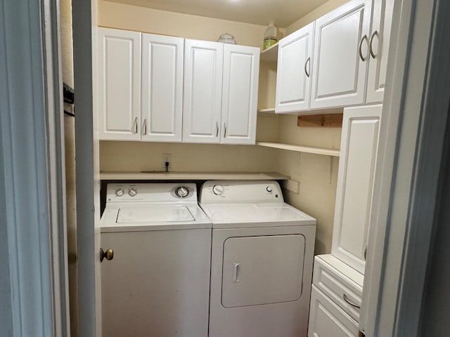 clothes washing area with washing machine and clothes dryer and cabinet space