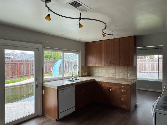 kitchen with white appliances, visible vents, dark wood finished floors, decorative backsplash, and a sink