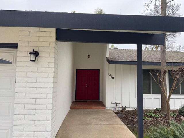 view of exterior entry with roof with shingles