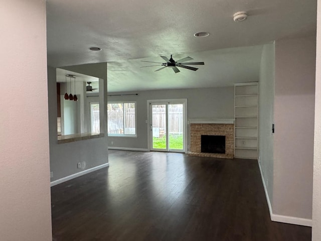 unfurnished living room featuring dark wood-style floors, a fireplace, ceiling fan, and baseboards