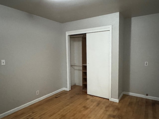 unfurnished bedroom featuring a closet, baseboards, and wood finished floors