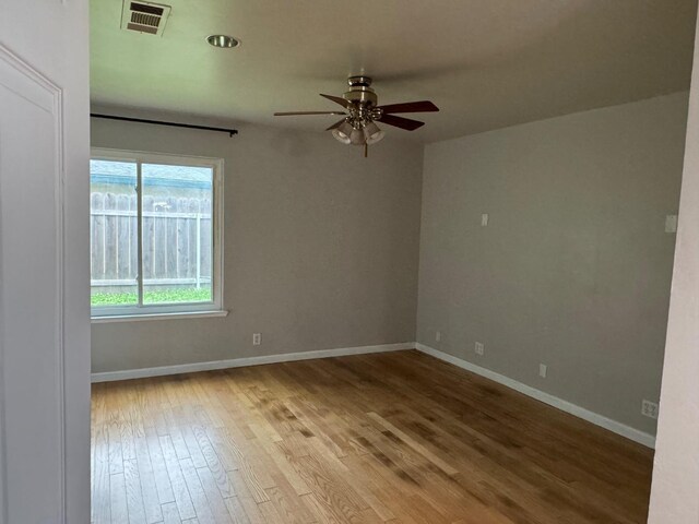 unfurnished room with baseboards, visible vents, ceiling fan, and wood finished floors