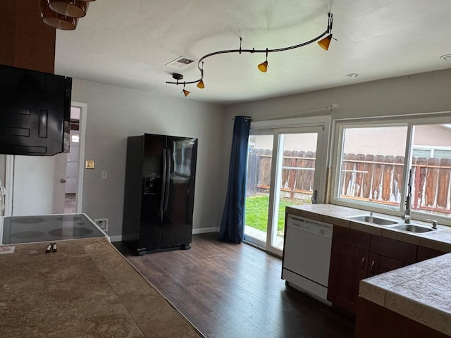 kitchen with dark wood finished floors, white dishwasher, black fridge, a sink, and range with electric stovetop