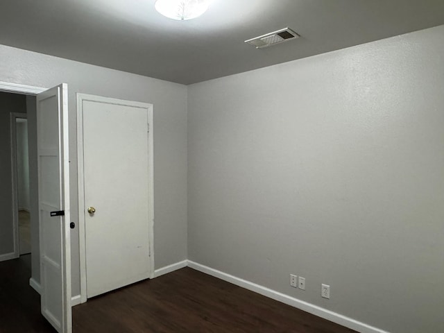 unfurnished room featuring baseboards, visible vents, and dark wood-style flooring