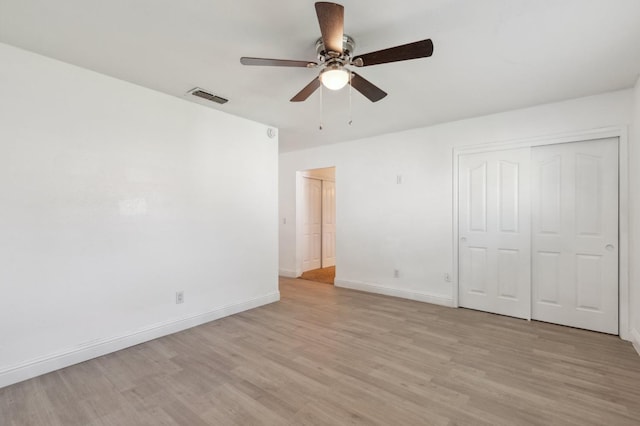 unfurnished bedroom featuring baseboards, visible vents, a ceiling fan, light wood-type flooring, and a closet