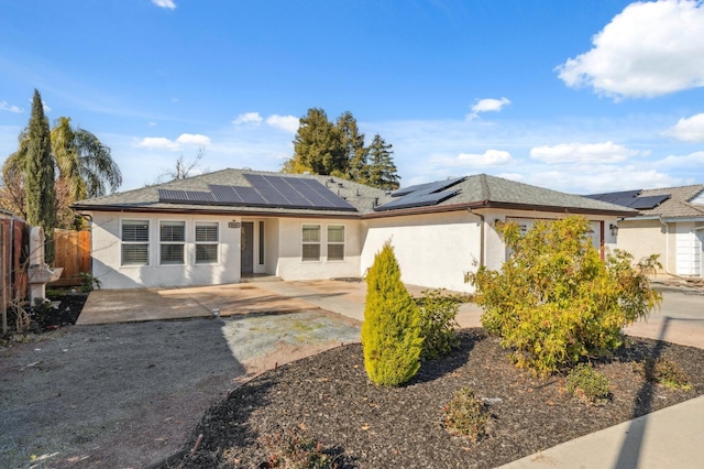 view of front of house with a patio, fence, solar panels, and stucco siding