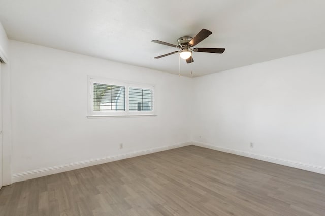 spare room featuring wood finished floors, a ceiling fan, and baseboards