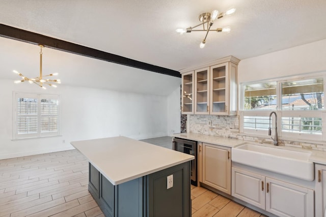 kitchen with sink, a chandelier, lofted ceiling with beams, a kitchen island, and backsplash