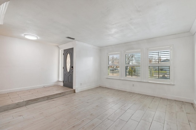 empty room with baseboards, visible vents, and light wood finished floors