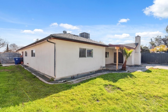 back of property with central AC unit, a yard, and a patio