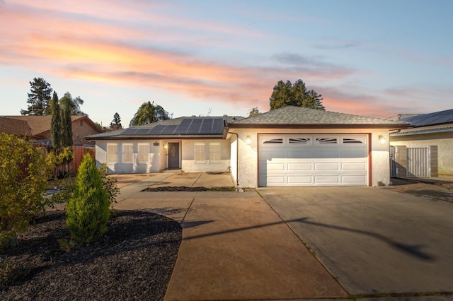 single story home with a garage and solar panels