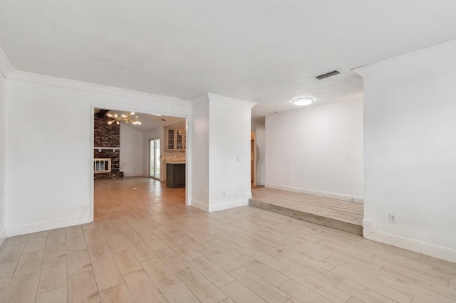 unfurnished room with light wood-style floors, visible vents, a fireplace, and crown molding