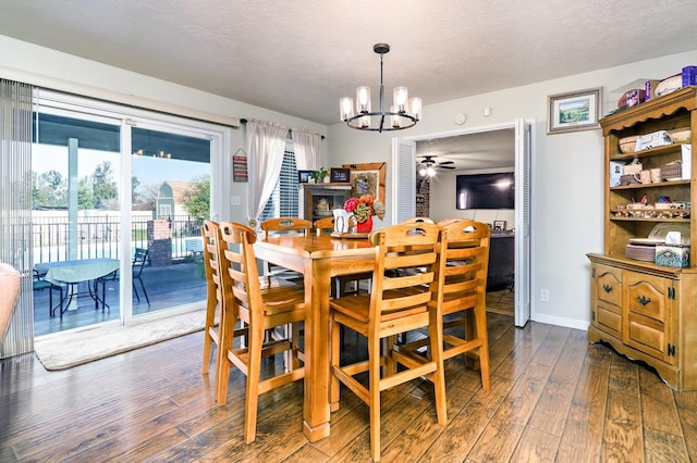 dining space featuring dark wood-type flooring, ceiling fan with notable chandelier, and a textured ceiling