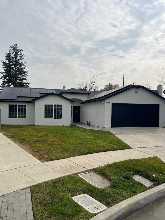 view of front of home with a garage, a front yard, and solar panels