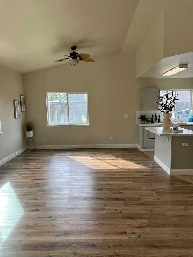 unfurnished living room with vaulted ceiling, a healthy amount of sunlight, and light wood-type flooring