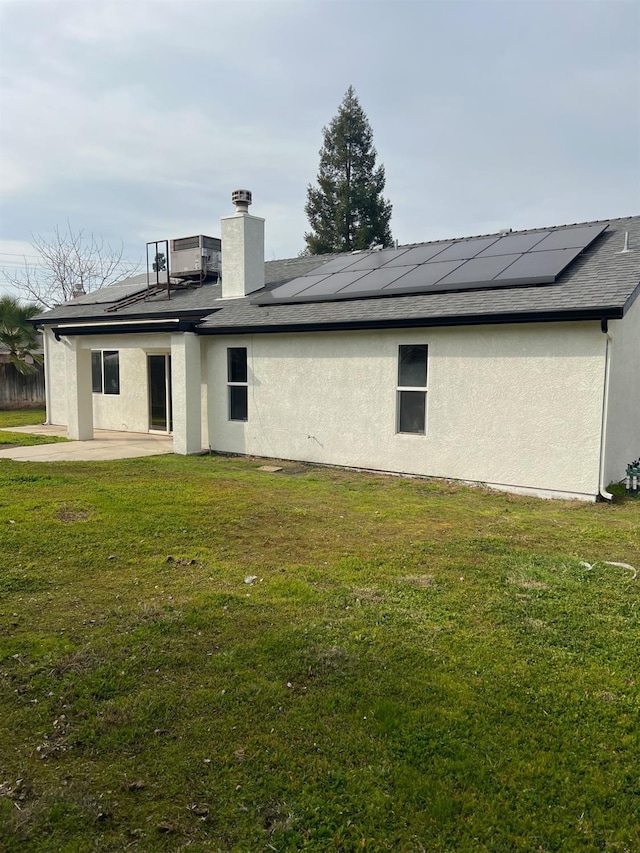 rear view of house with cooling unit, a yard, a patio, and solar panels