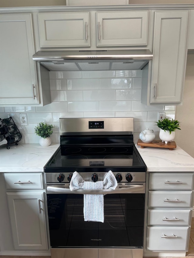 kitchen with stainless steel range with electric stovetop, backsplash, white cabinetry, and light stone counters