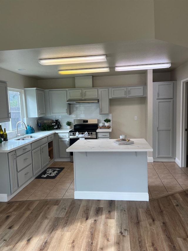 kitchen featuring electric stove, sink, tasteful backsplash, and a center island