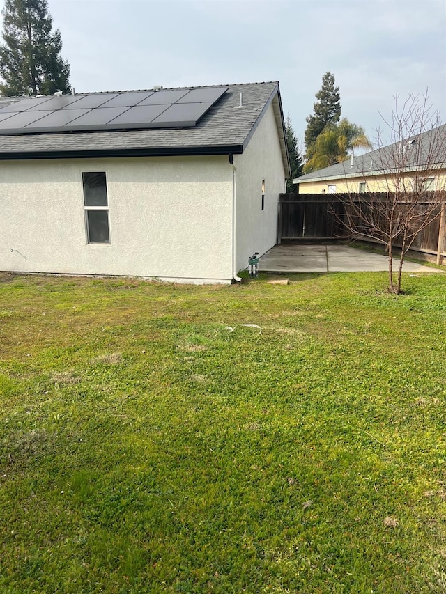 view of side of home with solar panels, a patio, and a lawn