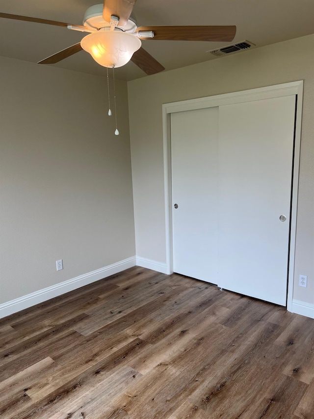 unfurnished bedroom featuring hardwood / wood-style floors, a closet, and ceiling fan