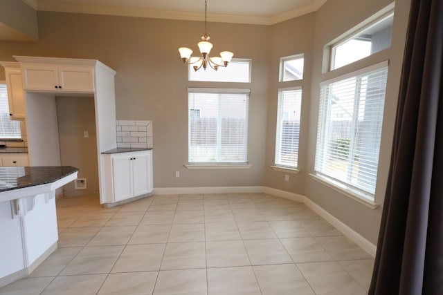 kitchen featuring white cabinetry, tasteful backsplash, ornamental molding, decorative light fixtures, and dark stone counters