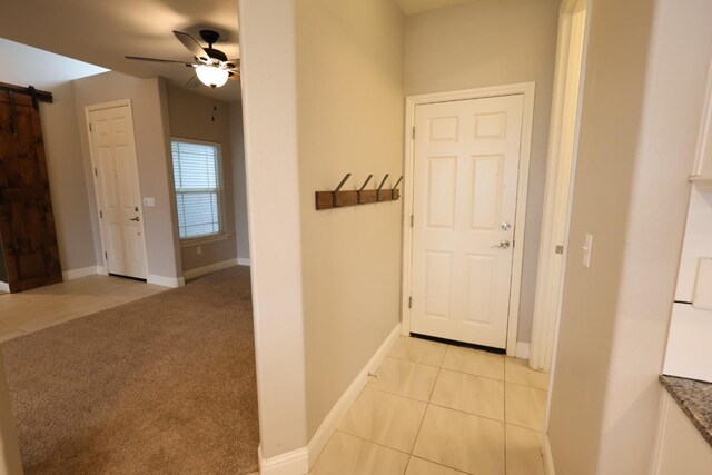 corridor featuring light colored carpet and a barn door