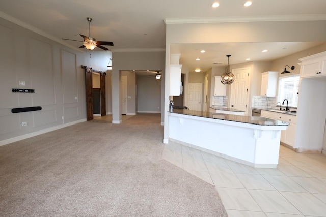 kitchen with kitchen peninsula, white cabinets, pendant lighting, a barn door, and backsplash