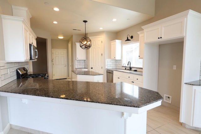 kitchen with white cabinetry, hanging light fixtures, stainless steel appliances, and kitchen peninsula