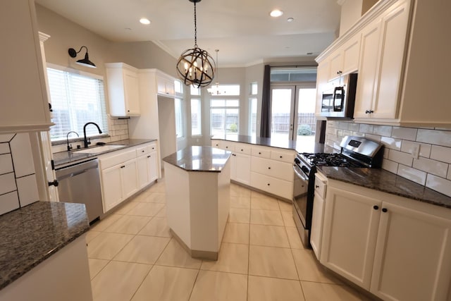 kitchen with stainless steel appliances, sink, a kitchen island, and white cabinets