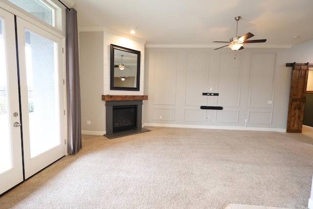 unfurnished living room with ceiling fan, ornamental molding, light carpet, and a fireplace