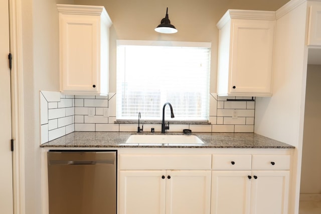 kitchen with stainless steel dishwasher, dark stone countertops, sink, and white cabinets