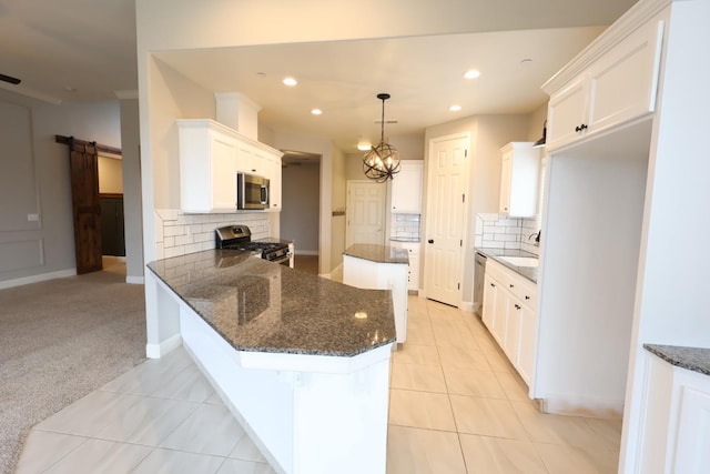 kitchen with a barn door, appliances with stainless steel finishes, and white cabinets