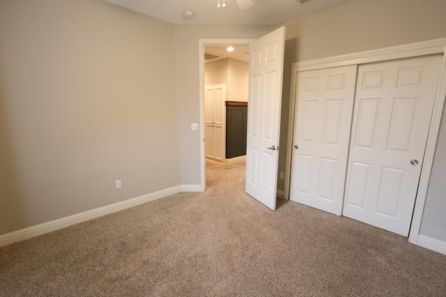 unfurnished bedroom with light carpet, a closet, and ceiling fan