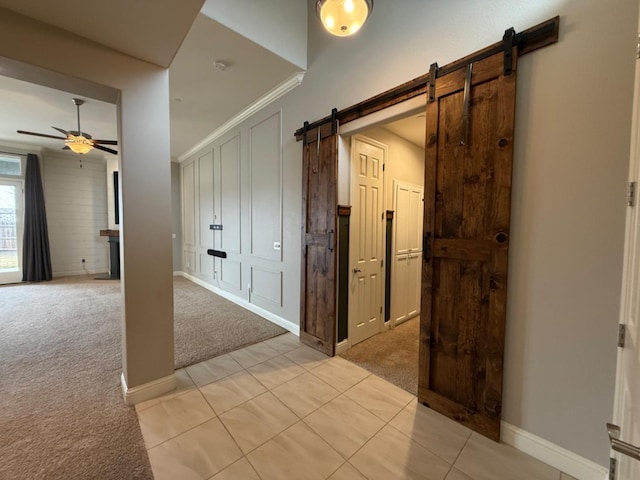 corridor with a barn door and light colored carpet