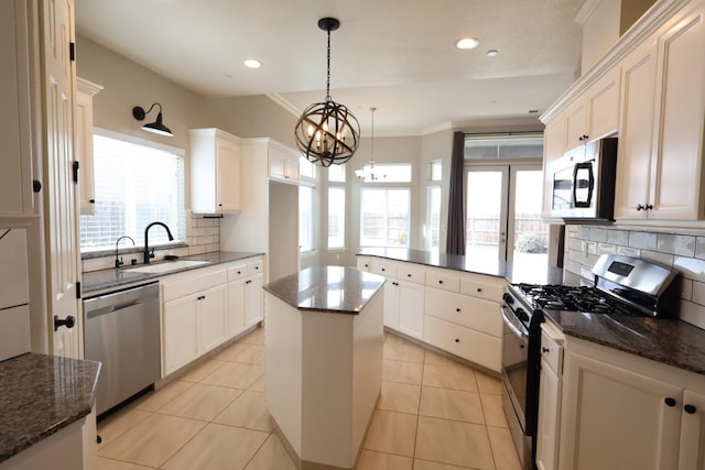 kitchen with sink, appliances with stainless steel finishes, white cabinetry, a kitchen island, and decorative backsplash