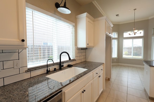 kitchen featuring sink, white cabinets, backsplash, dark stone counters, and ornamental molding