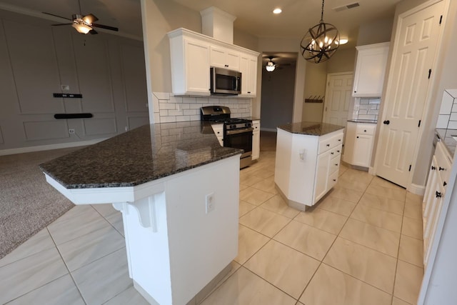 kitchen with a center island, light tile patterned floors, appliances with stainless steel finishes, ceiling fan with notable chandelier, and white cabinets