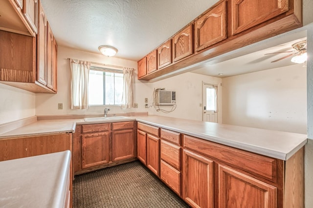 kitchen with sink, a wall mounted AC, ceiling fan, kitchen peninsula, and a textured ceiling