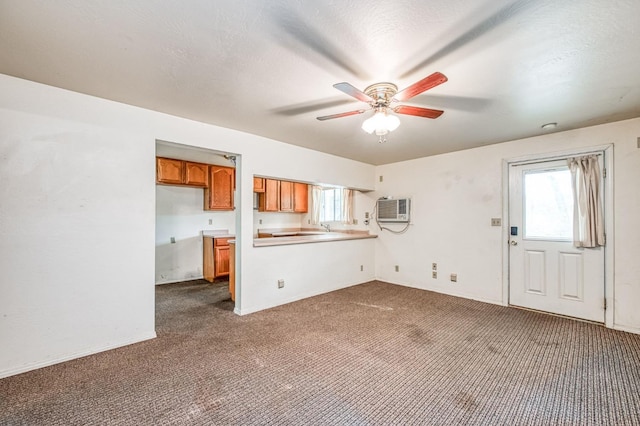 unfurnished living room featuring plenty of natural light, dark carpet, a wall mounted air conditioner, and ceiling fan