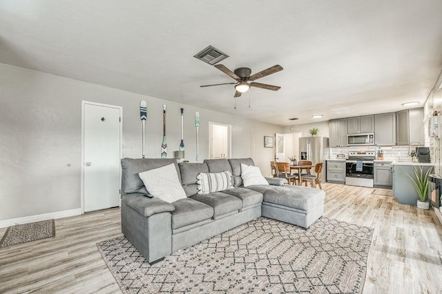 living room featuring sink, ceiling fan, and light wood-type flooring