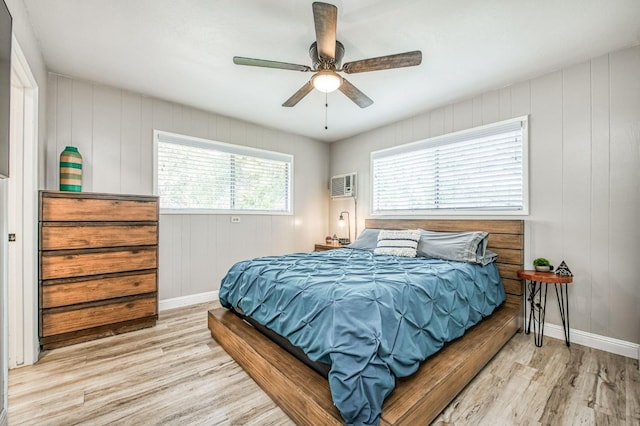 bedroom featuring ceiling fan, a wall mounted AC, and light hardwood / wood-style floors