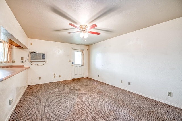 unfurnished room featuring carpet floors, a wall mounted air conditioner, a textured ceiling, and ceiling fan