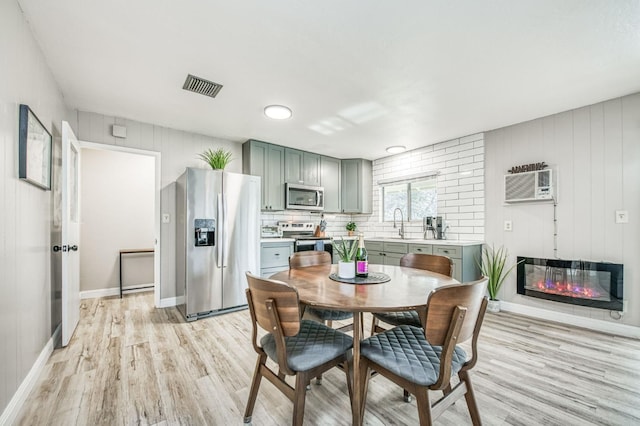 dining room with sink, light hardwood / wood-style floors, and a wall unit AC