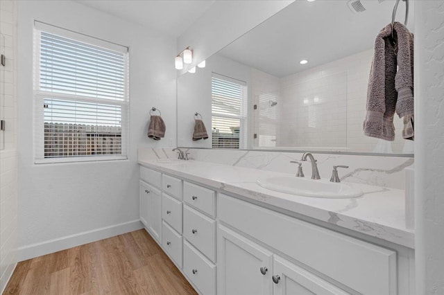 bathroom with hardwood / wood-style flooring, vanity, and tiled shower