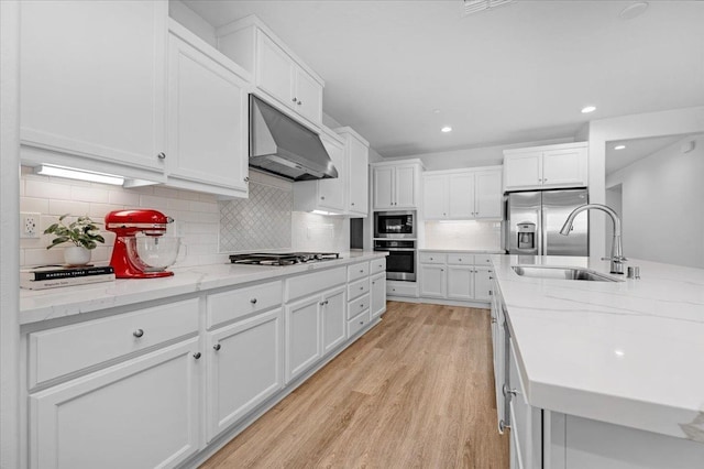 kitchen with stainless steel appliances, light stone countertops, light hardwood / wood-style flooring, and white cabinets