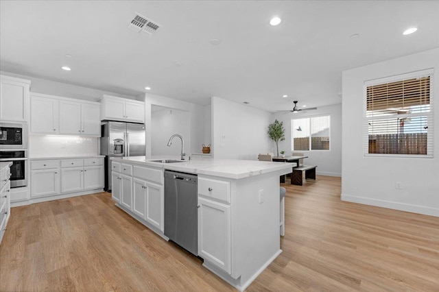 kitchen featuring sink, light hardwood / wood-style flooring, an island with sink, stainless steel appliances, and white cabinets