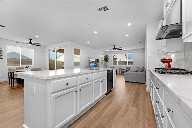 kitchen with sink, white cabinetry, a center island with sink, light wood-type flooring, and range hood