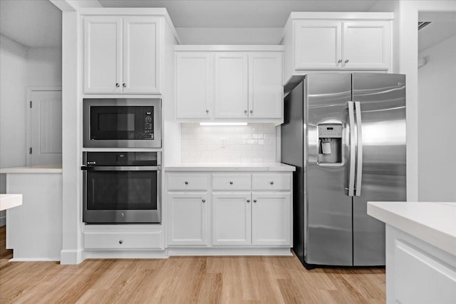 kitchen featuring stainless steel appliances, white cabinetry, backsplash, and light hardwood / wood-style floors