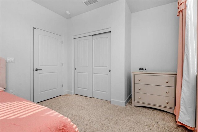 bedroom featuring light colored carpet and a closet