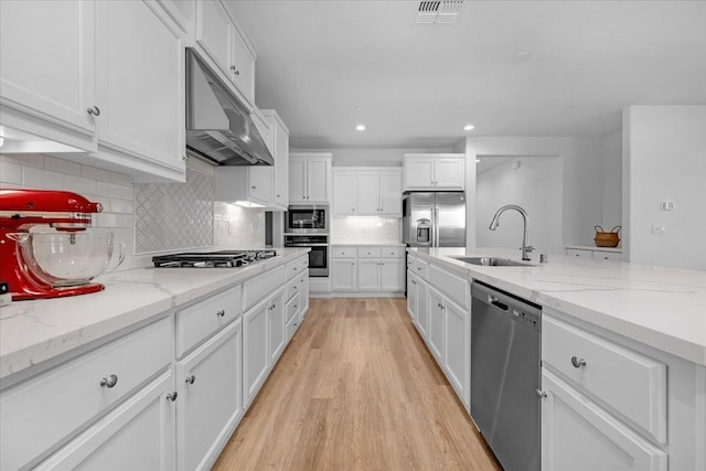 kitchen featuring sink, white cabinetry, stainless steel appliances, light stone counters, and light wood-type flooring